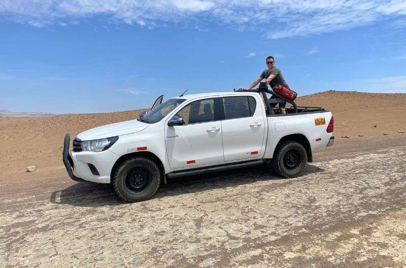 Traveler and his car in Paracas National Reserve in Peru, photo by Next Level of Travel