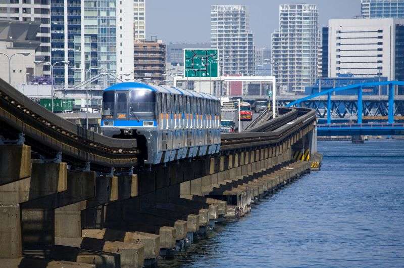 The Tokyo monorail traveling along the river in Tokyo with high-rise buildings in the background