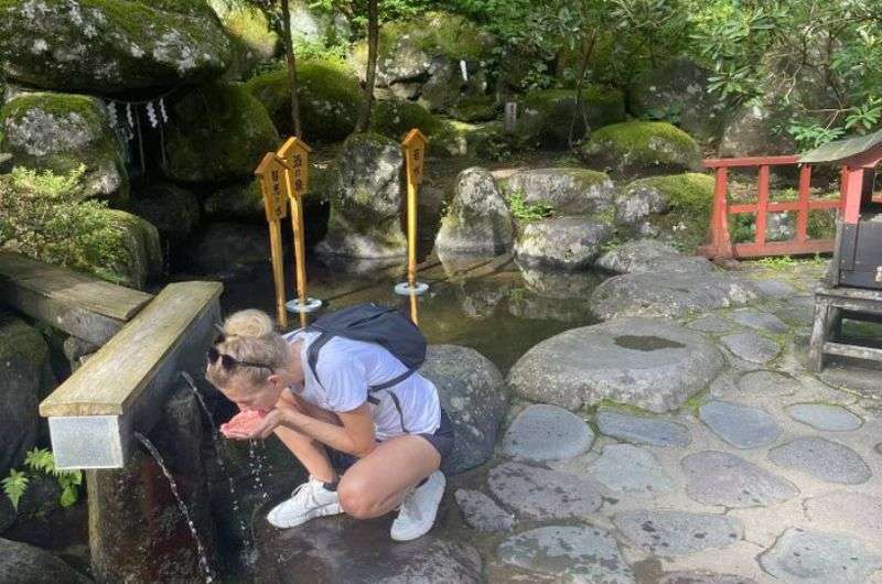 A woman drinking spring water at Futarasan Shrine in Nikko, a top thing to do in Japan Nikko
