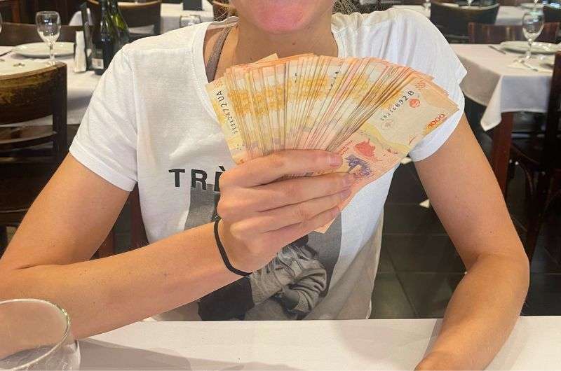 Tourist and the pesos banknotes in Argentina, photo by Next Level of Travel