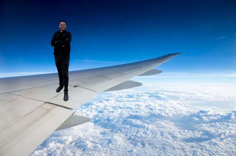 Traveler flying on the wing of an airplane