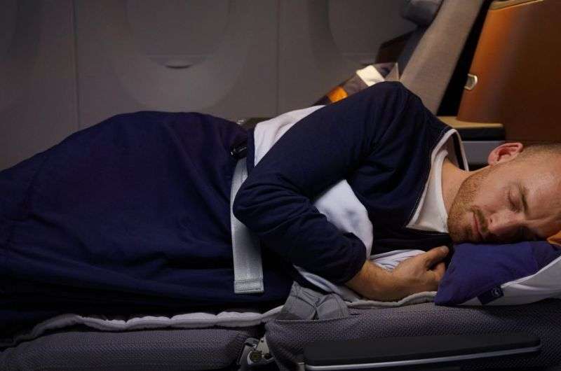 Passenger sleeping comfortably in a fully reclined airline seat